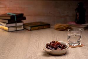 Many Date Palms are on bowls, plates, a cup of water, and the Quran, islamic style lamps on wooden tables, to wait for the time of Iftar, with the concept of ramadan Muslims around the world. photo