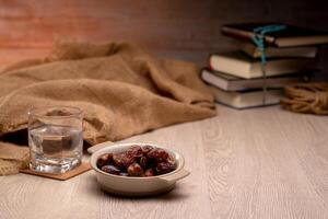 Many Date Palms are on bowls, plates, a cup of water, and the Quran, islamic style lamps on wooden tables, to wait for the time of Iftar, with the concept of ramadan Muslims around the world. photo