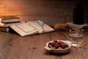 Many Date Palms are on bowls, plates, a cup of water, and the Quran, islamic style lamps on wooden tables, to wait for the time of Iftar, with the concept of ramadan Muslims around the world. photo