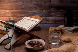 Many Date Palms are on bowls, plates, a cup of water, and the Quran, islamic style lamps on wooden tables, to wait for the time of Iftar, with the concept of ramadan Muslims around the world. photo