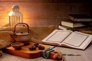 Many Date Palms are on bowls, plates, a cup of water, and the Quran, islamic style lamps on wooden tables, to wait for the time of Iftar, with the concept of ramadan Muslims around the world. photo