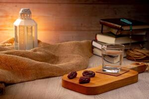 Many Date Palms are on bowls, plates, a cup of water, and the Quran, islamic style lamps on wooden tables, to wait for the time of Iftar, with the concept of ramadan Muslims around the world. photo