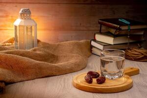 Many Date Palms are on bowls, plates, a cup of water, and the Quran, islamic style lamps on wooden tables, to wait for the time of Iftar, with the concept of ramadan Muslims around the world. photo