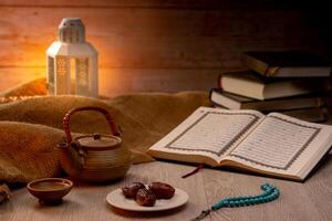 Many Date Palms are on bowls, plates, a cup of water, and the Quran, islamic style lamps on wooden tables, to wait for the time of Iftar, with the concept of ramadan Muslims around the world. photo