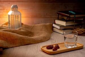 Many Date Palms are on bowls, plates, a cup of water, and the Quran, islamic style lamps on wooden tables, to wait for the time of Iftar, with the concept of ramadan Muslims around the world. photo