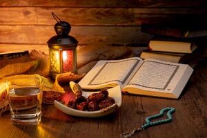 Many Date Palms are on bowls, plates, a cup of water, and the Quran, islamic style lamps on wooden tables, to wait for the time of Iftar, with the concept of ramadan Muslims around the world. photo