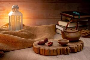 Many Date Palms are on bowls, plates, a cup of water, and the Quran, islamic style lamps on wooden tables, to wait for the time of Iftar, with the concept of ramadan Muslims around the world. photo