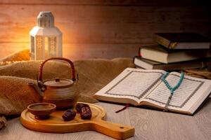 Many Date Palms are on bowls, plates, a cup of water, and the Quran, islamic style lamps on wooden tables, to wait for the time of Iftar, with the concept of ramadan Muslims around the world. photo