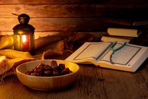 Many Date Palms are on bowls, plates, a cup of water, and the Quran, islamic style lamps on wooden tables, to wait for the time of Iftar, with the concept of ramadan Muslims around the world. photo