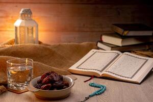 Many Date Palms are on bowls, plates, a cup of water, and the Quran, islamic style lamps on wooden tables, to wait for the time of Iftar, with the concept of ramadan Muslims around the world. photo