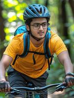 Determined Indian man mountain biking through lush forest trail photo