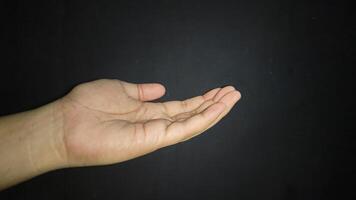 The hand is raised showing a gesture of asking for something. Isolated on black background photo