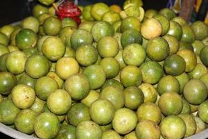 A bowl full of green limes sitting on top of a table photo