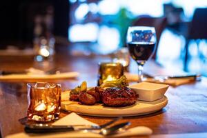 Beef steak meat with vegetables and sauce served with red wine and candles photo