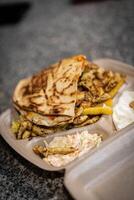 Breaded fried chicken breast with fries and onion rings, in a cardboard tray with wooden cutlery. Environmentally friendly disposable plastic free container photo