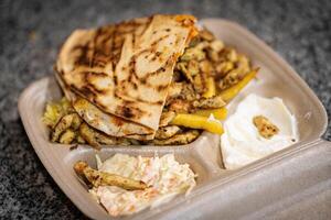 Breaded fried chicken breast with fries and onion rings, in a cardboard tray with wooden cutlery. Environmentally friendly disposable plastic free container photo