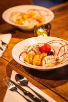 split ice cream with syrup and strawberry on white plate, side view. Chocolate, strawberry and vanilla ice cream scoops on plate, summer dessert Vertical photo