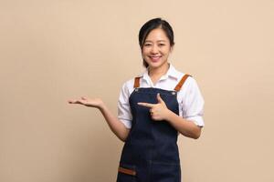 Cheerful Asian barista in apron showing advertisement or special offers by pointing at banner. photo