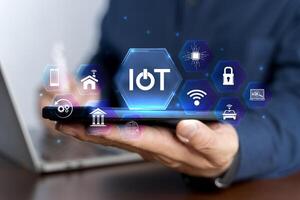 Smart business IOT, internet of things concept. Businessman use laptop with virtual IOT icon for connecting to internet photo