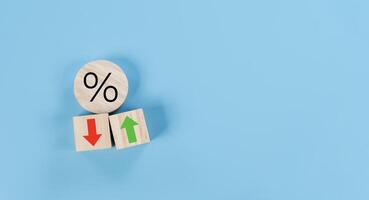 Percentage icon on wooden cube block and up and down arrow symbol on flipping white dice on blue background photo