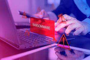 Malware attack virus alert. Person use laptop with virtual warning sign with ransomware word photo