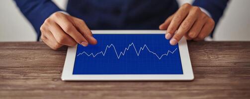Hands using tablet to analyze data graph on wooden table. photo