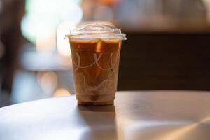 Close up and selective focus glass of ice latte on black table at coffee shop. photo