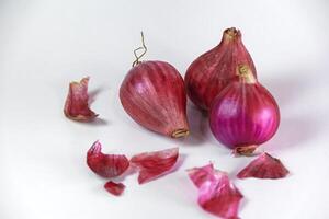three shallots and their skin crumbs isolated on white photo