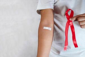 close up showing arm after injection and holding red ribbon photo