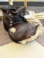 Artistic clay boot with straw details on outdoor display table photo