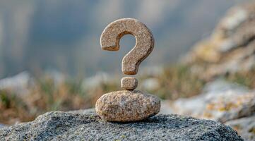 A question mark is sitting on top of a rock photo