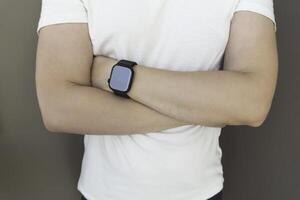 Attractive unknown man in white t-shirt sporting a smartwatch, smart watch on male hand to track sport activity, man with crossed hands photo