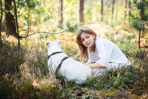 A child relaxing with a dog in a serene forest, surrounded by greenery and blooming flowers on a sunny day photo