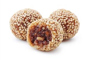 Three sesame-coated balls filled with sweet paste, a popular snack or dessert. photo