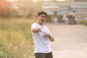 a man standing and smiling. the man points at the camera in the sunny afternoon. photo