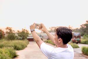 a man who is taking photos of himself and nature in various styles. the man has his back to the camera. set on a sunny afternoon in nature.