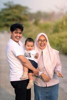 A young family that looks happy and laughing out loud with mother, father and baby boy. photo taken vertically. photo atmosphere in nature.