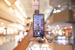 a man's hand taking pictures of objects in the mall. the man is seen using his cellphone to take pictures of objects around him. the portrait results are very clear and good. photo