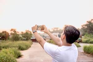 a man who is taking photos of himself and nature in various styles. the man has his back to the camera. set on a sunny afternoon in nature.