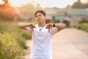 a man standing with a thumbs down. The man acted like someone was underestimating something. set in nature on a sunny afternoon. photo