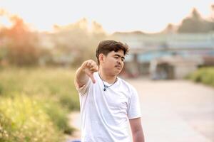 a man standing with a thumbs down. The man acted like someone was underestimating something. set in nature on a sunny afternoon. photo