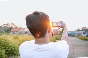 a man who is taking photos of himself and nature in various styles. the man has his back to the camera. set on a sunny afternoon in nature.