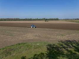 Tractor processes, plows agricultural field, top view, background. photo