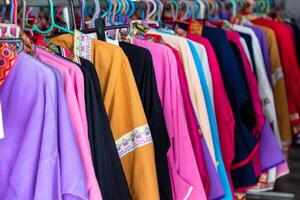 Colorful clothes of cotton fabric hanging on rail in store photo