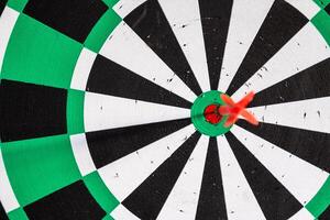 Dart arrow in bullseye target on dartboard photo