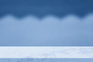 White Marble Table Corner with Roof Shadow on the Dark Blue Concrete Wall Background, Suitable for Product Presentation Backdrop, Display, and Mock up. photo