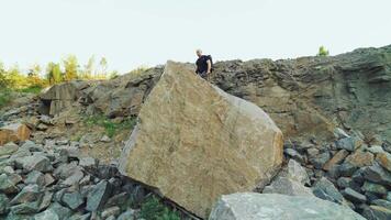 a brave traveler is standing on top of a huge rock with his hands raised on the background of a beautiful location in the summer video