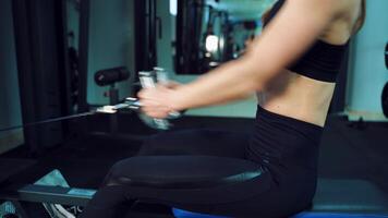 A woman is sitting behind a cardio trainer and working with her hands to strengthen the muscles of her arms and chest in the gym. Close-up. Blurred Background video