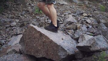 traveler shod in black sneakers is walking on the rocks in a hike in the summer video