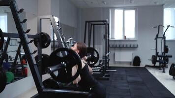 A strong woman in black sportswear performs an exercise with a barbell in the gym. Squatting. video